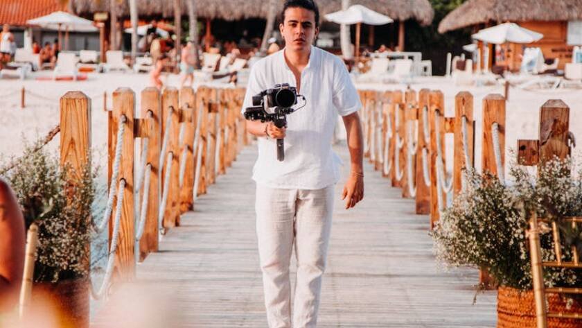 a man holding a camera while standing on the wooden boardwalk